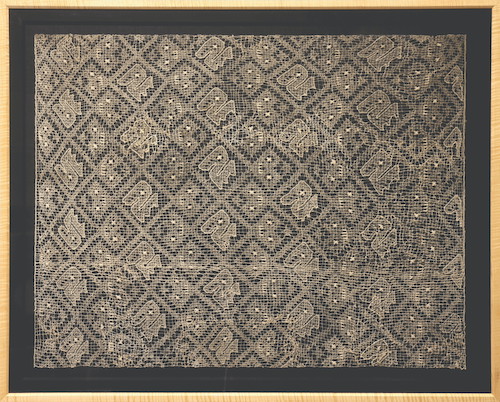 A framed light-colored gauze textile with square patterns throughout.