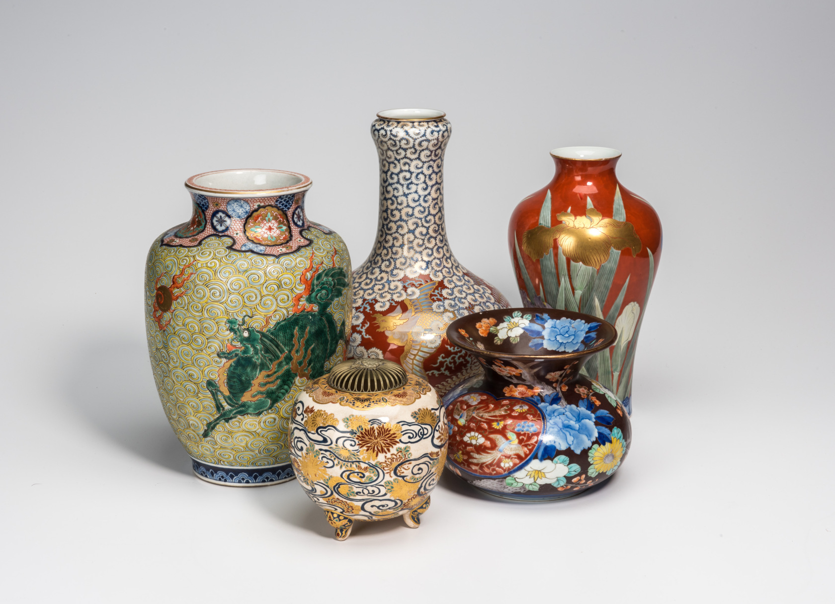 A grouping of five ornately-decorated vases in bright colors.