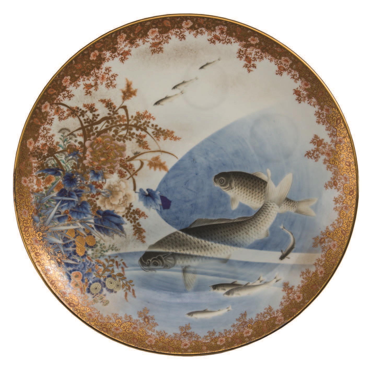 An ornate round dish with two large fish against a blue and white background. Around the edge is a gold floral design.
