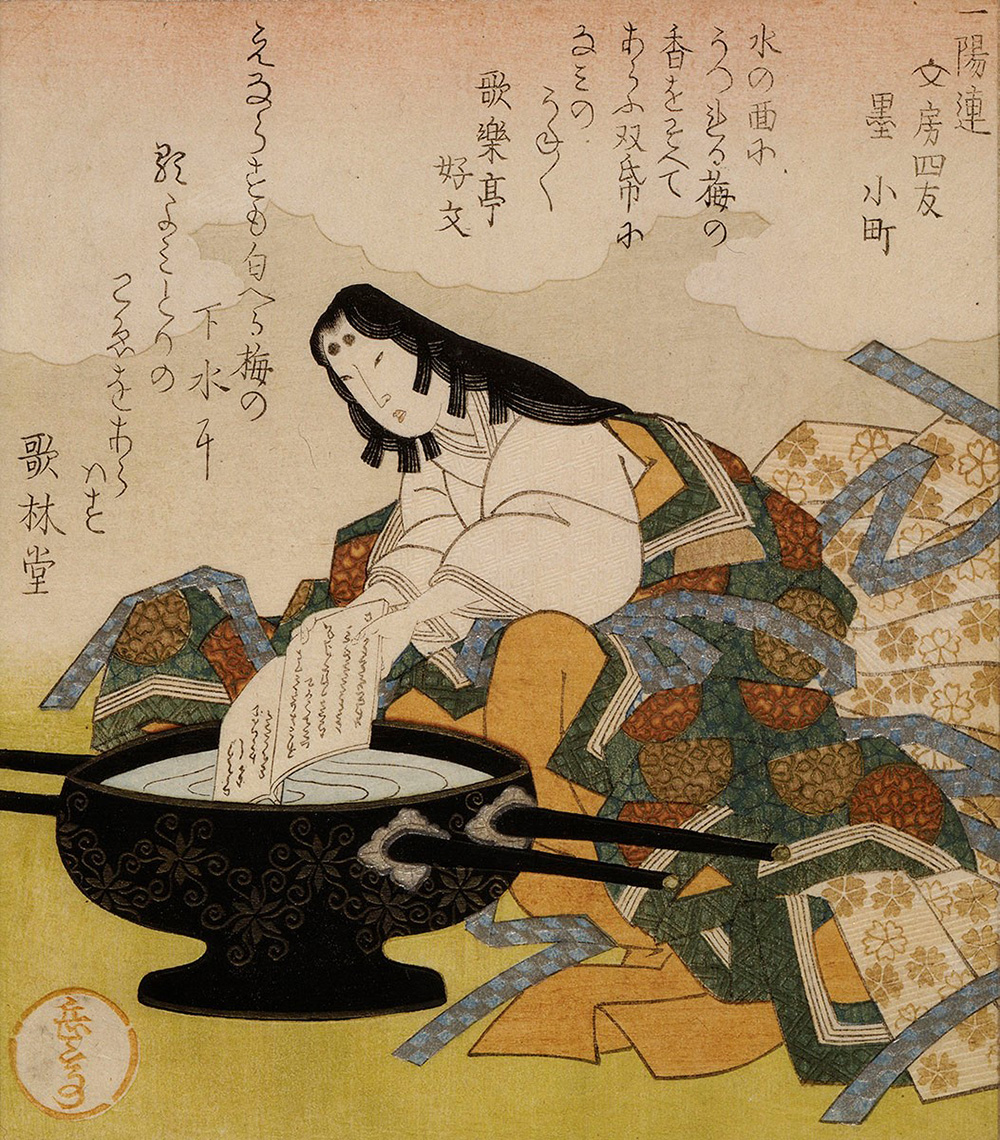 A woman holds a book with writing on it.  She appears to be dipping it into a large bowl filled with water.