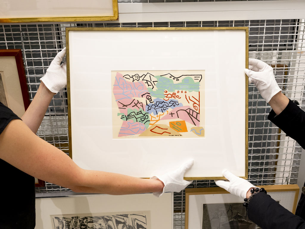 Two sets of hands hold a framed, colorful watercolor or print.