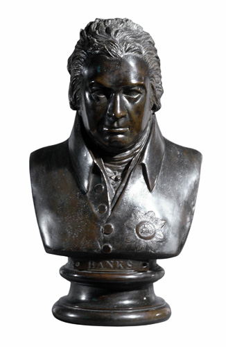 A bust of a man with short hair brushed away from his face, and a serious, intent expression. He has a jacket with a high collar and a flower on the left chest.