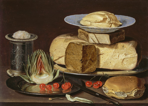 A table is stacked with food on two silver platters. On the smaller platter, a halved artichoke is sitting up next to a few bright red cherries. On the larger platter, half a wheel of cheese sits with a a smaller wedge next to it, a third wedge on top, and a small plate on top of the cheese pile. A metal jar or canister is nearby. In front of the platters, a round loaf and three cherries sit directly on the table.